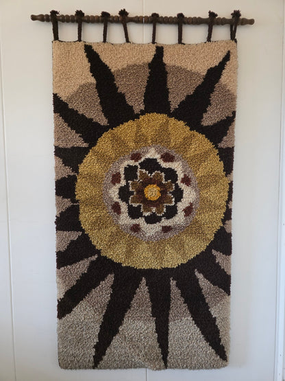 Vintage wandkleed met grote bloem in okergeel, bruin en beige aan een houten ophangstok